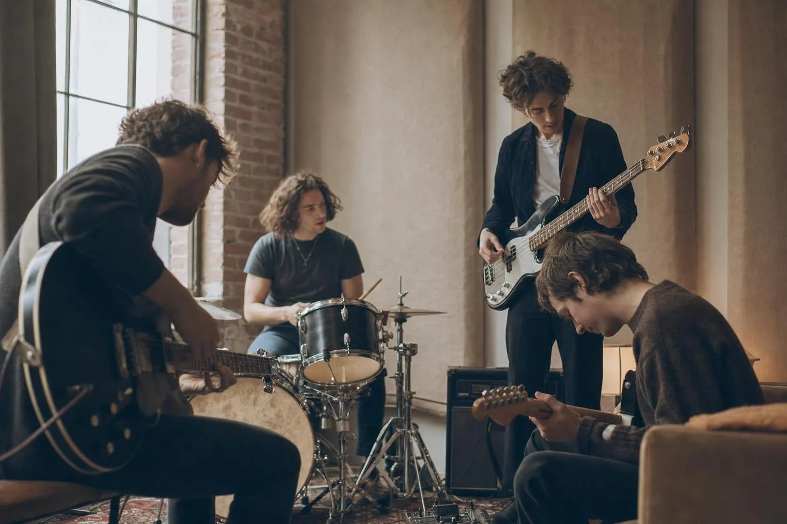 A four-piece indie rock band mid-song on a small club stage, guitar amps and drum kit lit by warm stage lights